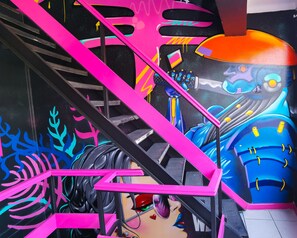 A staircase with pink railings and a mural of a robot and a woman. - hotel velero express (Iquique)