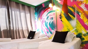 Une chambre d’hôtel avec deux lits, une fresque murale abstraite et colorée, et un plafond vert.
