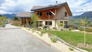 Ein modernes, zweistöckiges Haus mit geneigtem Dach, großen Fenstern und einem gepflegten Garten mit gepflegter Schotterauffahrt.