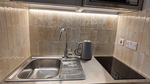 A compact kitchen with a stainless steel sink, a microwave, and a built-in oven.
