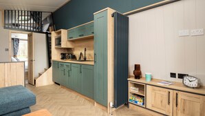 Una cocina compacta con armarios verdes, una encimera de madera y un microondas integrado.