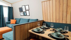 Una habitación acogedora con un separador de madera, un sofá color turquesa y una zona de comedor con platos, fuentes y vasos.
