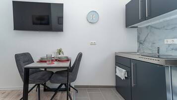 Una cocina moderna con armarios grises, un lavamanos de acero inoxidable y un televisor de pantalla plana montado en la pared.