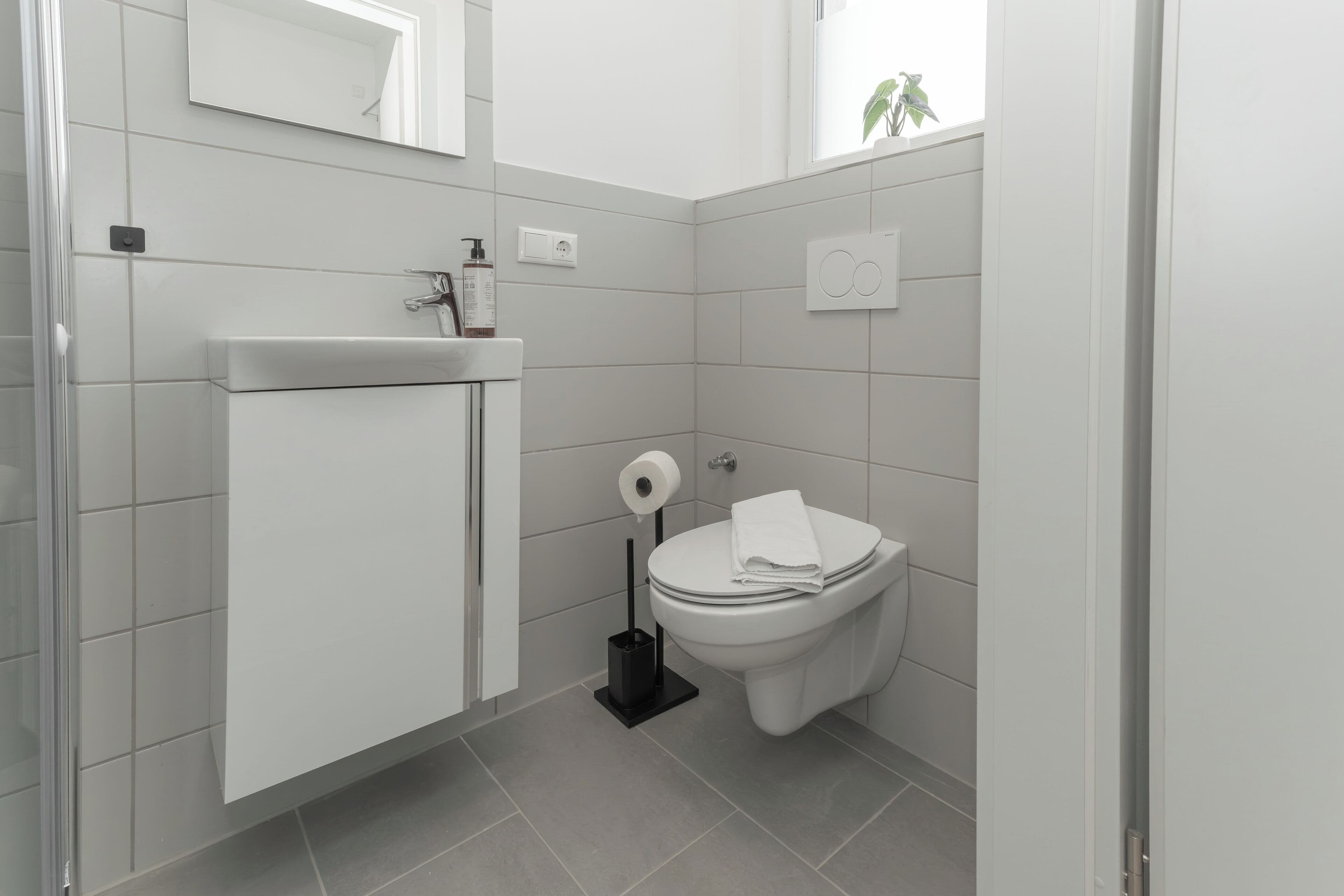 Ein modernes Badezimmer mit Toilette, Waschbecken und Spiegel.