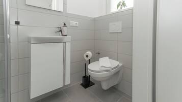 Ein modernes Badezimmer mit Toilette, Waschbecken und Spiegel.