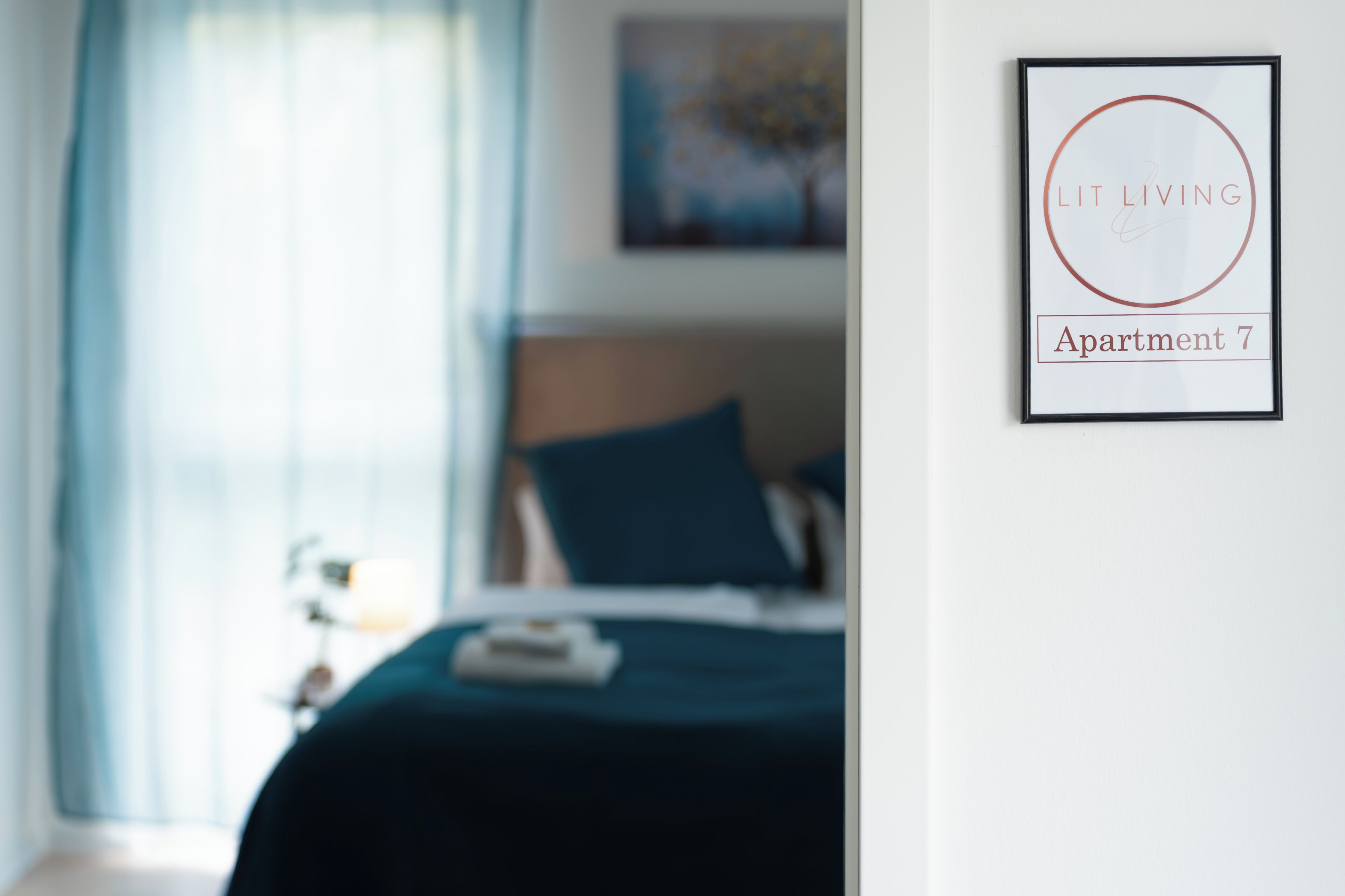 Ein Schlafzimmer mit Bett, Nachttisch, Lampe und einem gerahmten Schild an der Wand.