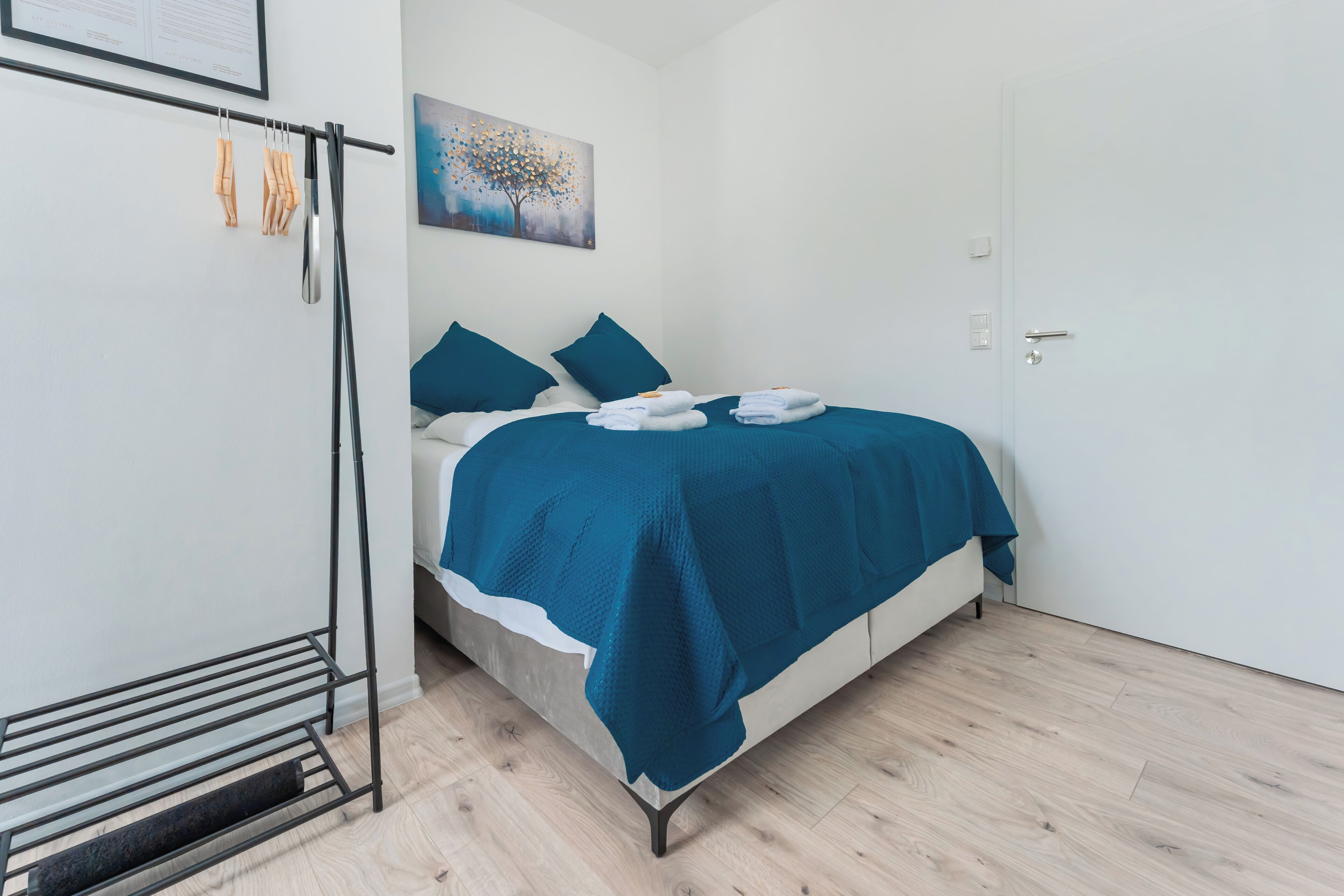A bedroom with a bed, a painting, and a door.