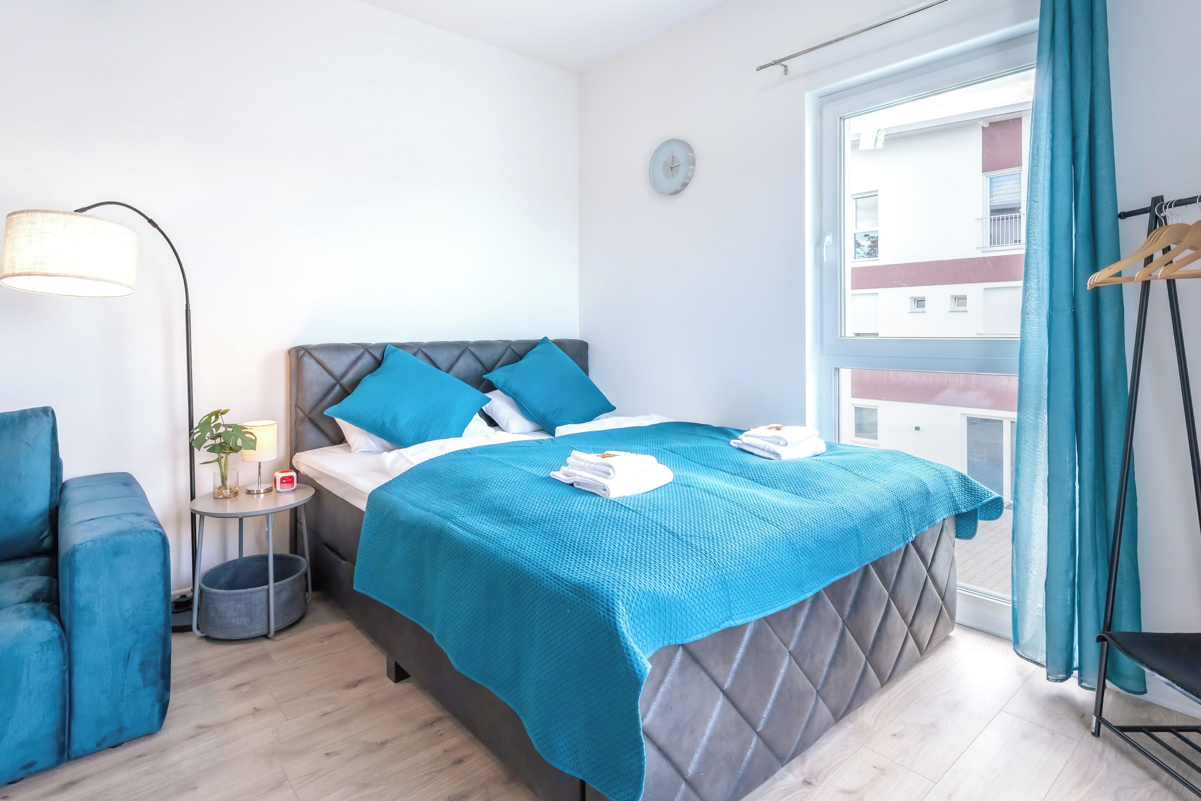A modern bedroom with a bed, a side table, a chair, and a window with curtains.