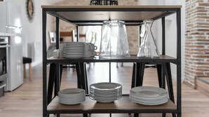 A kitchen with a wooden table displaying stacked plates and glassware. - Le Duplex du Castel haut - Escapade Tarnaise (CASTELNAU DE MONTMIRAL)