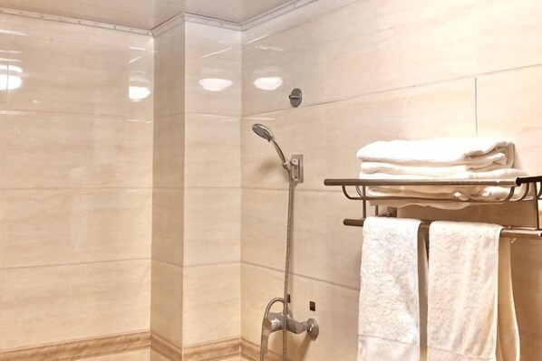 A shower with a handheld showerhead, a towel rack with folded towels, and a wall-mounted towel rack. - Yina Inn (Lijiang Ancient City Dashuiche) (Lijiang)