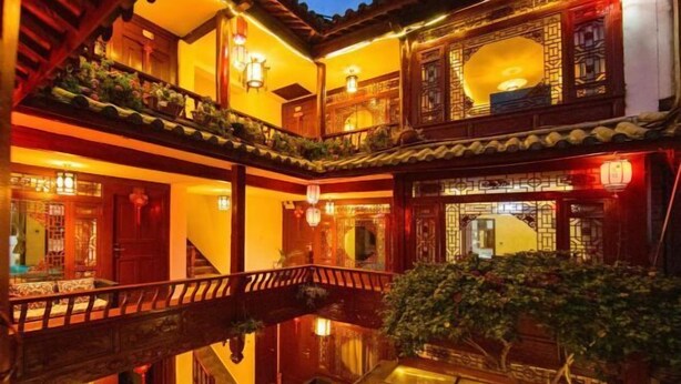 A traditional Chinese courtyard with wooden balconies, lanterns, and a central water feature.