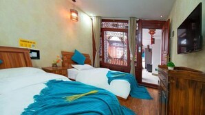 A hotel room with two beds, a TV, and a wooden cabinet.