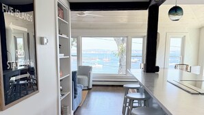 A modern kitchen with a large island, bar stools, and a view of the sea. - Five Islands Waterfront Retreat (Georgetown)