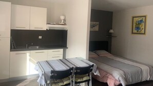 A compact room with a kitchenette, a bed, and a small table with chairs.