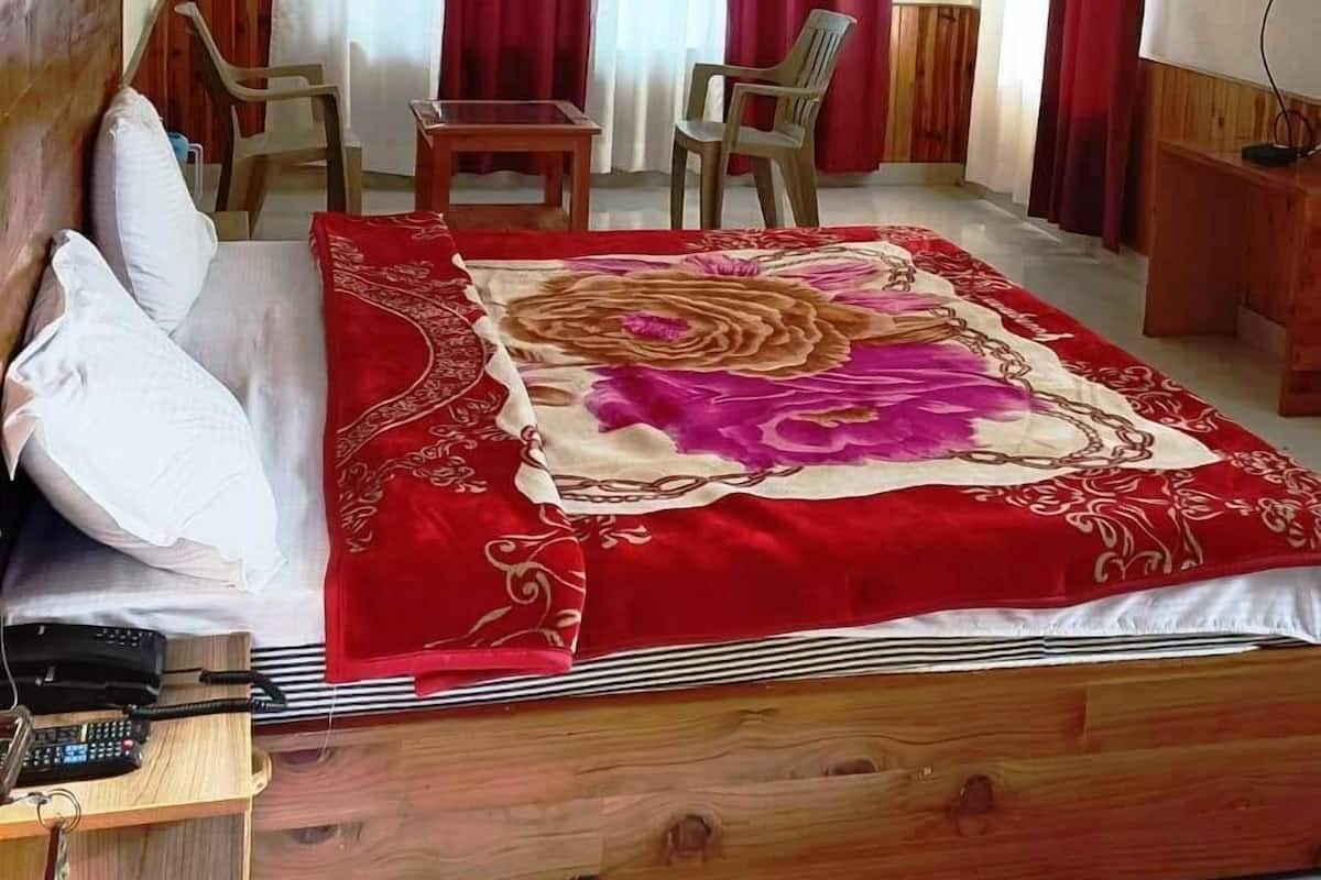 A bedroom with a wooden bed, red curtains, a ceiling fan, a TV, and a desk with a chair.