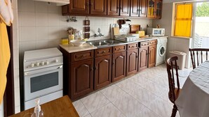 Una cocina compacta con armarios de madera, horno empotrado, microondas y lavamanos.