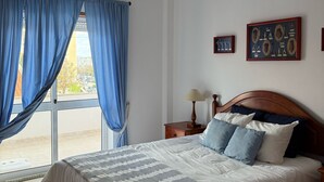 Una cama bien hecha con una colcha a rayas, un cabecero de madera y una mesita de noche con una lámpara.