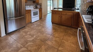 A spacious kitchen with a stainless steel refrigerator, white stove, and wooden cabinets.