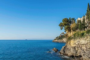 A coastal hotel with a view of the sea, rocky cliffs, and a clear sky. - Central Cozy Nest With Parking Bogliasco (Bogliasco)