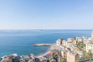 A coastal town with buildings along the waterfront, a pier, and a boat in the distance. - Central Cozy Nest With Parking Bogliasco (Bogliasco)