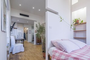 Relax in a serene space with a neatly made bed, a comfortable chair, and a touch of greenery.