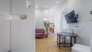 A modern living room with a wooden floor, a purple sofa, a dining table, and a TV mounted on the wall. - Central Cozy Nest With Parking Bogliasco (Bogliasco)