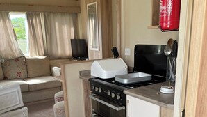 Une petite cuisine équipée d’une cuisinière, d’un four et d’un petit réfrigérateur.