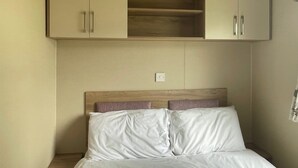 Une chambre à coucher avec un lit, deux armoires et une tête de lit en bois.