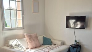 Ein modernes Wohnzimmer mit einem weißen Sofa, einer gestreiften Decke und einem kleinen Beistelltisch mit einer Pflanze.