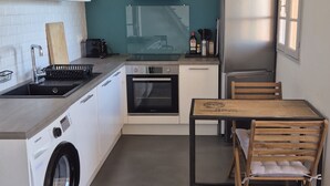 Eine kleine Küche mit Waschmaschine, Backofen und Edelstahlkühlschrank.