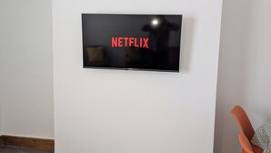 A flat-screen TV mounted on a white wall with the word "NETFLIX" displayed on the screen.