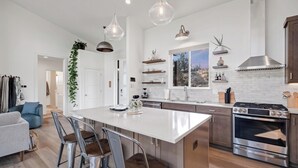 Una cocina moderna con una isla central, electrodomésticos de acero inoxidable e iluminación colgante.