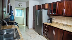 Una cocina con un lavamanos de acero inoxidable, un refrigerador de doble puerta, armarios de madera y una encimera de granito.