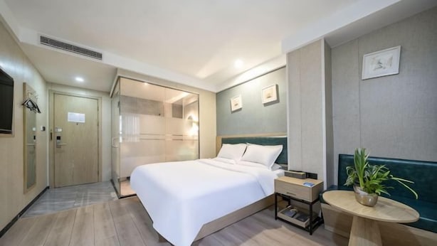 A hotel room with a bed, bedside table, and a small round table with a plant. - Waiting Qingju Hotel (9th People's Hospital Lujiabang Road Subway Station Branch) (Shanghai)