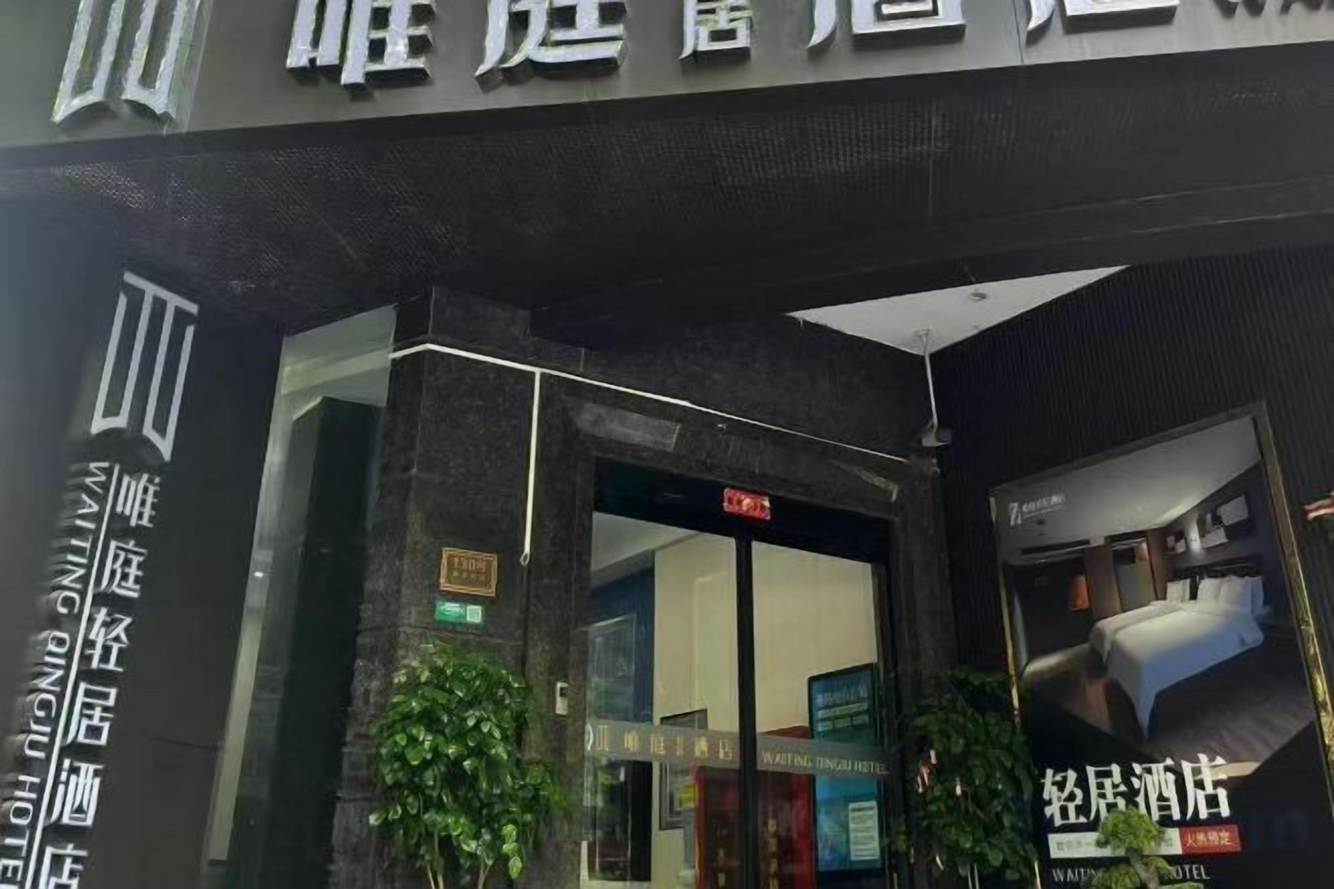 A hotel entrance with a glass door, a sign above the door, and a poster on the right side.