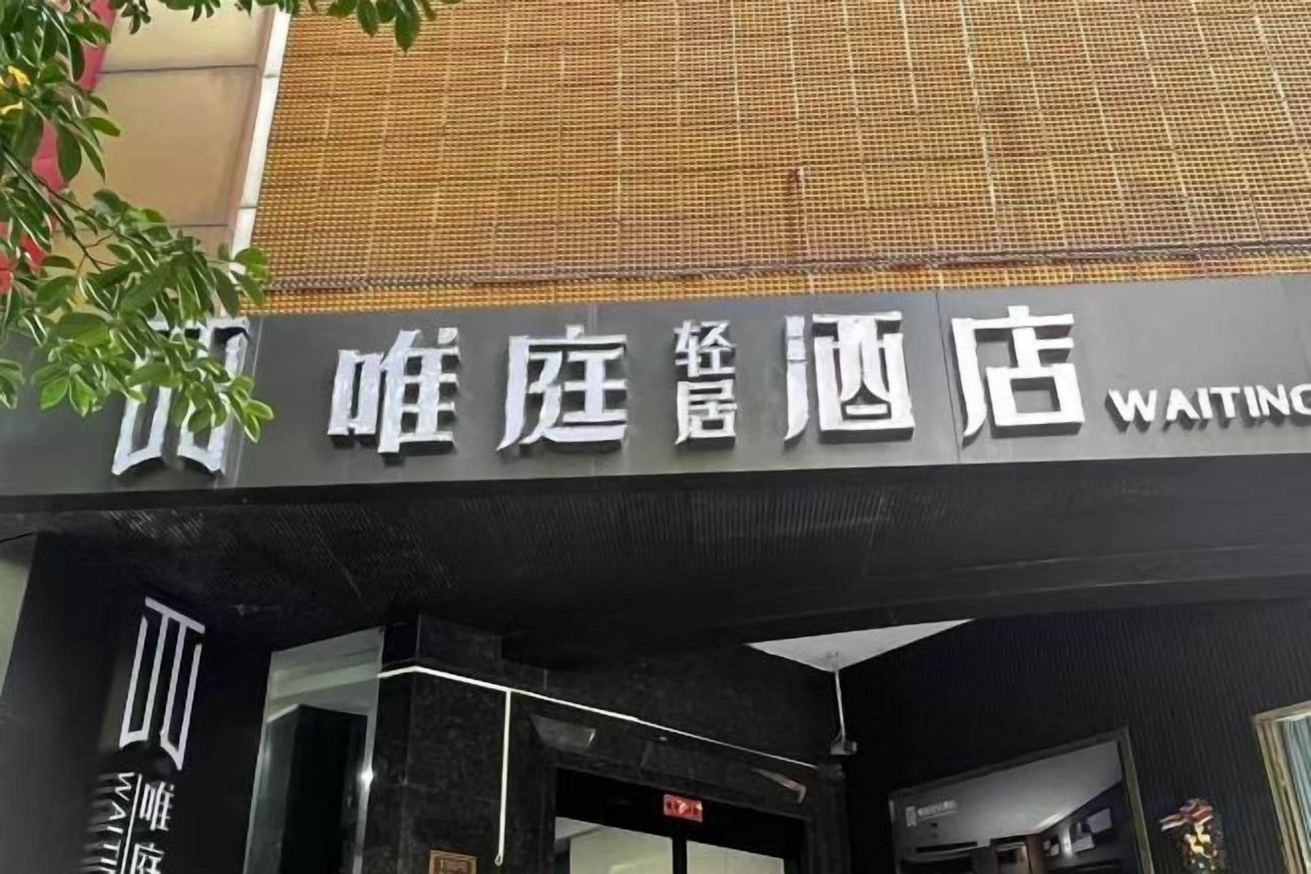 A hotel entrance with a sign in a foreign language and the word 'WAITING' in English.