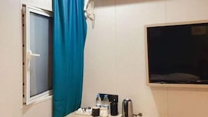 A hotel room with a window, a curtain, a flat-screen TV, a coffee maker, and a small table with toiletries. - Waiting Qingju Hotel (9th People's Hospital Lujiabang Road Subway Station Branch) (Shanghai)