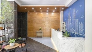 A reception area with a wooden wall, a marble reception desk, and a cityscape mural. - Waiting Qingju Hotel (9th People's Hospital Lujiabang Road Subway Station Branch) (Shanghai)