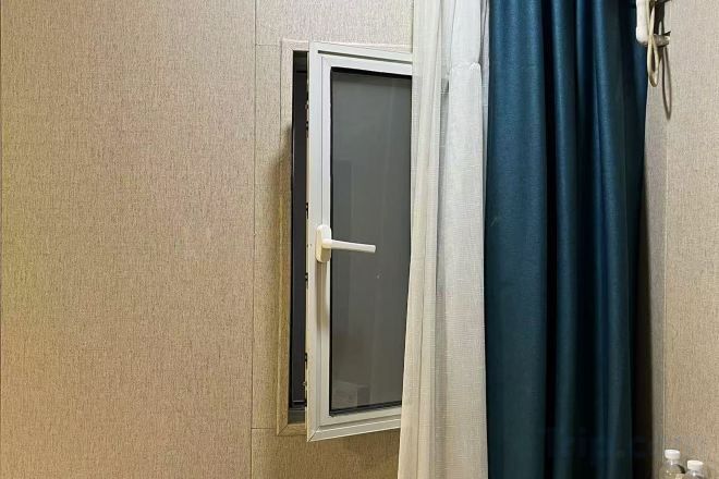 Una habitación con una puerta entreabierta, una ventana y una cortina.
