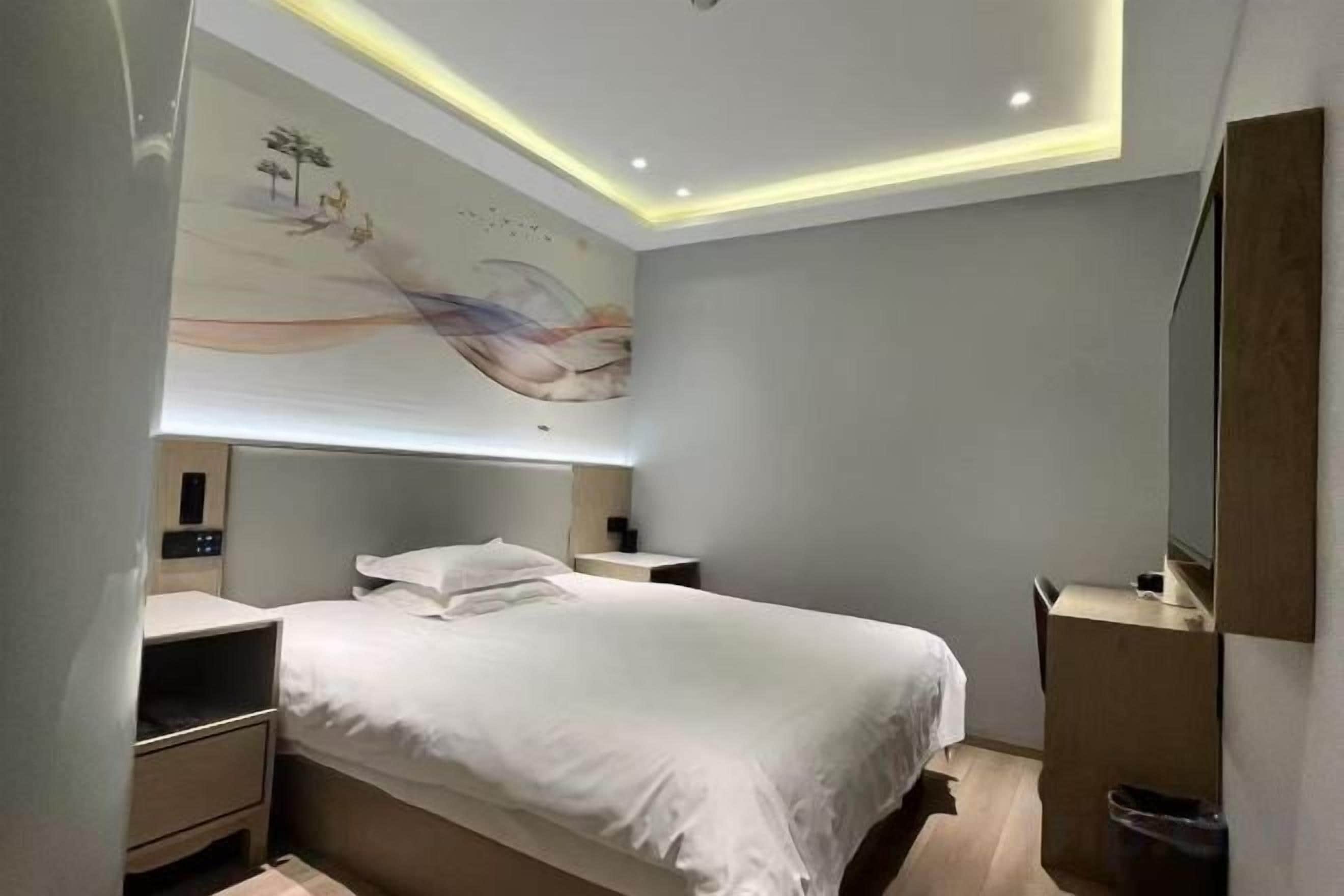 A modern bedroom with a bed, bedside tables, a nightstand, and a wall-mounted TV.
