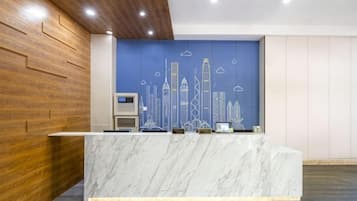 A reception desk with a marble top, a city skyline mural on the wall, and a wooden panel wall to the left.
