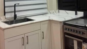 A kitchen with a sink, stove, and cabinets. - Kenzi Suites (Kisii)