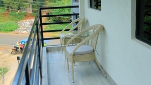 A balcony with wicker chairs and a table, overlooking a road with parked motorcycles. - Kenzi Suites (Kisii)