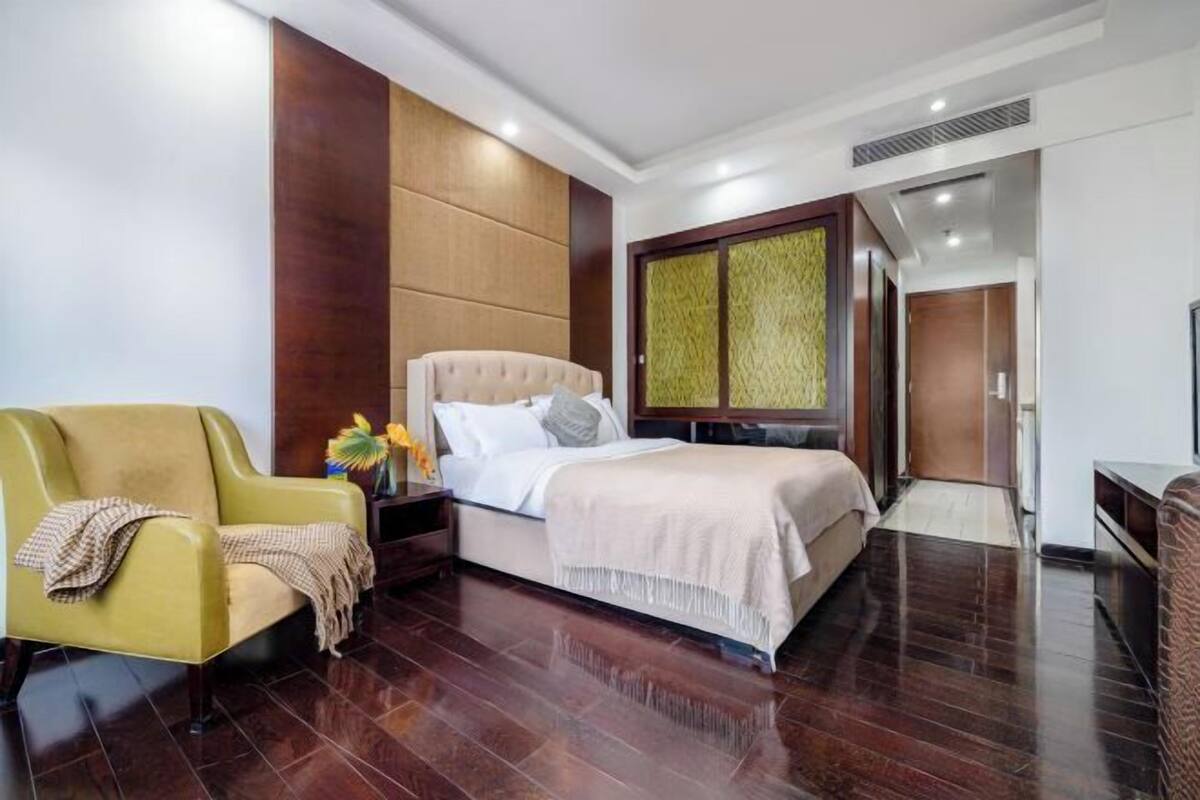A hotel room with a bed, a sofa, a nightstand, and a wardrobe.