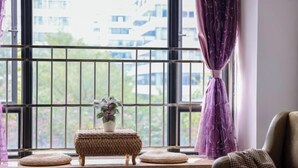 Una habitación con ventana, una mesita con una planta y una silla.