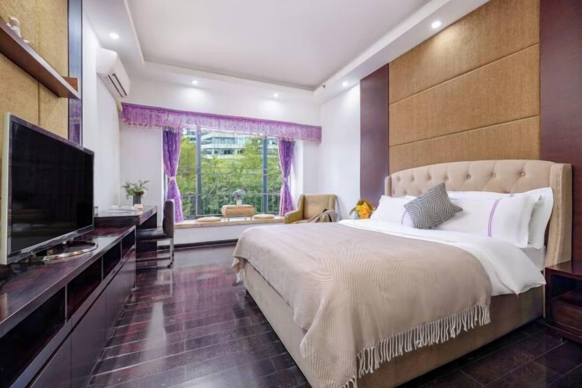 A modern bedroom with a large bed, a TV, and a window with curtains.