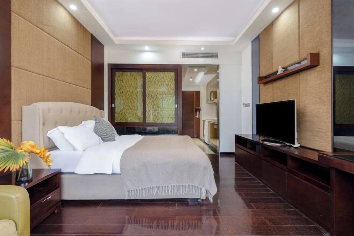 A modern hotel room with a large bed, a TV, and a decorative wall panel.
