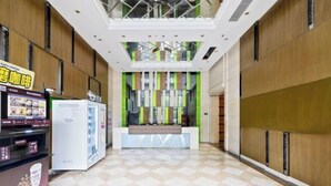 Un vestíbulo de hotel con una recepción, una cafetería y máquinas expendedoras.
