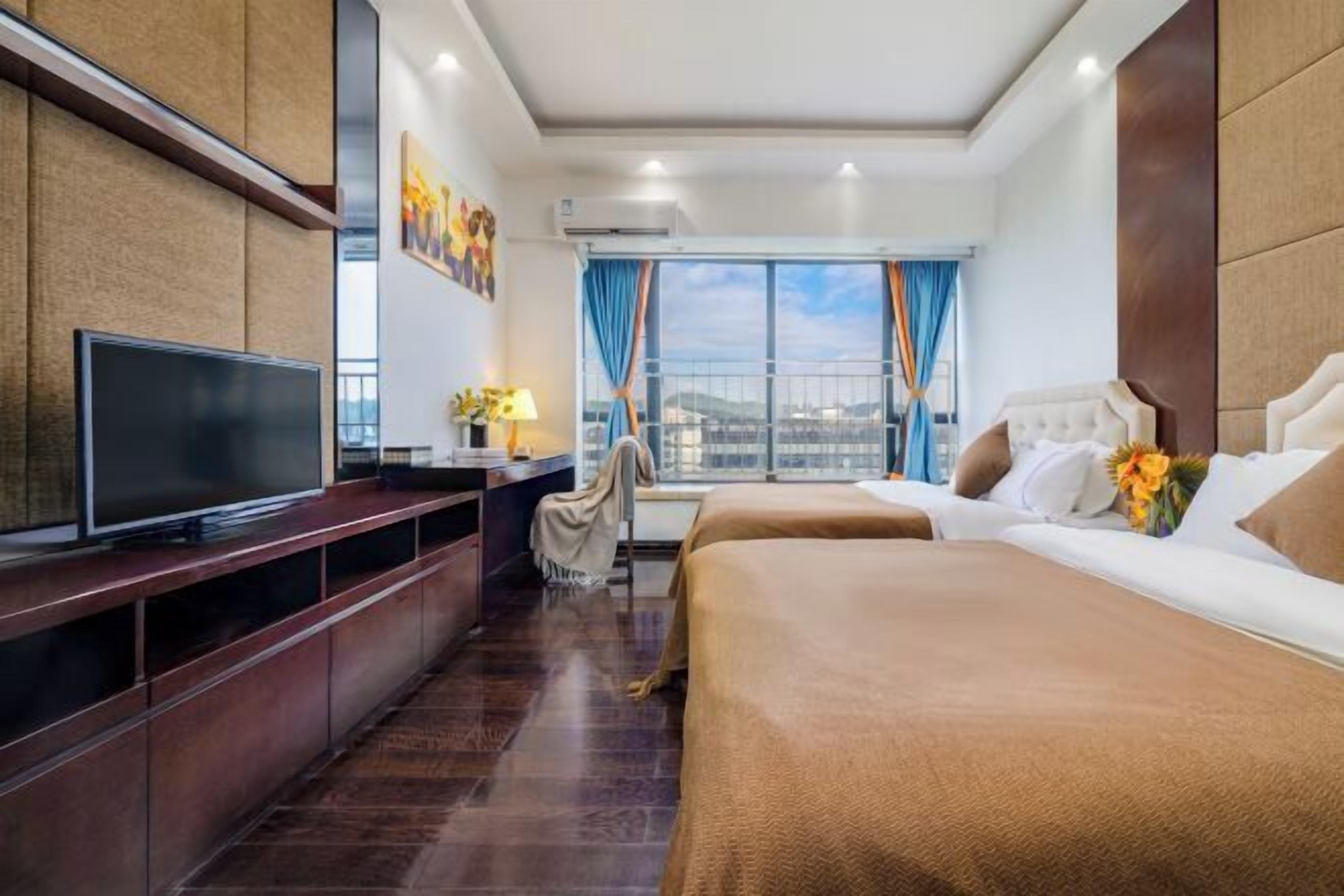 Una habitación de hotel con televisión, escritorio, cama y ventana con cortinas.