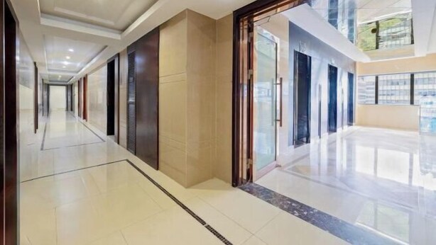 Un pasillo moderno de hotel con una puerta de cristal que da a una habitación luminosa.